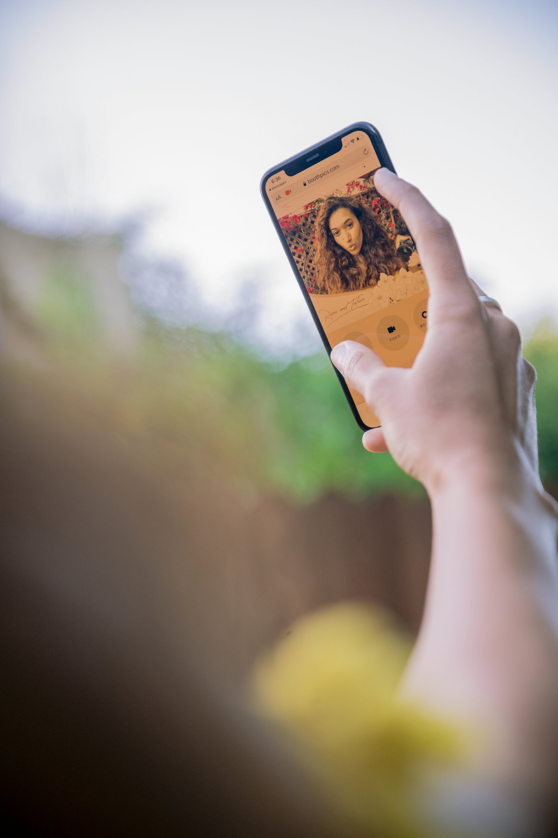 Person using a mobile device to access a Virtual Photobooth for taking photos.