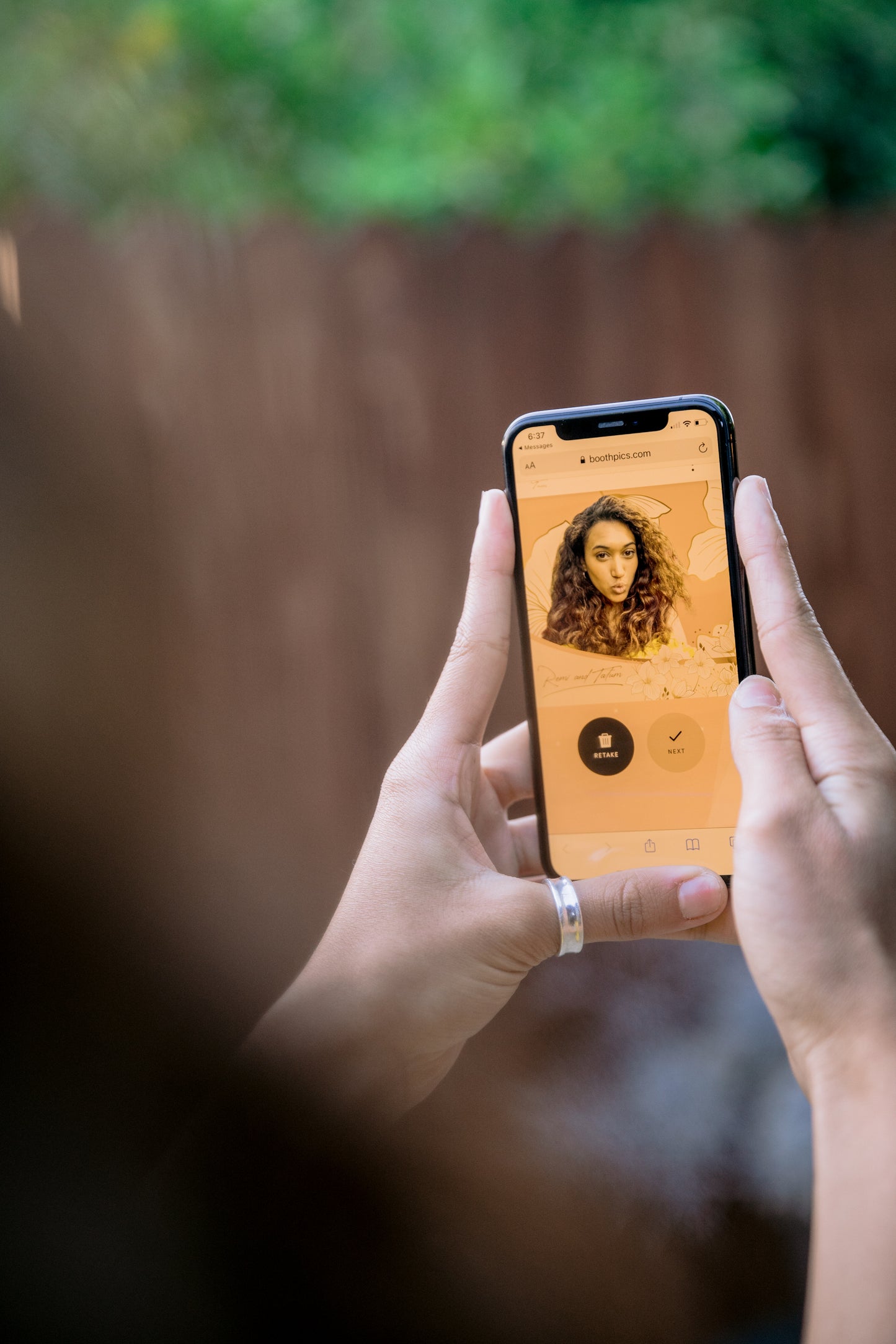A person using a smartphone to access a Virtual Photobooth app with a photo on the screen.